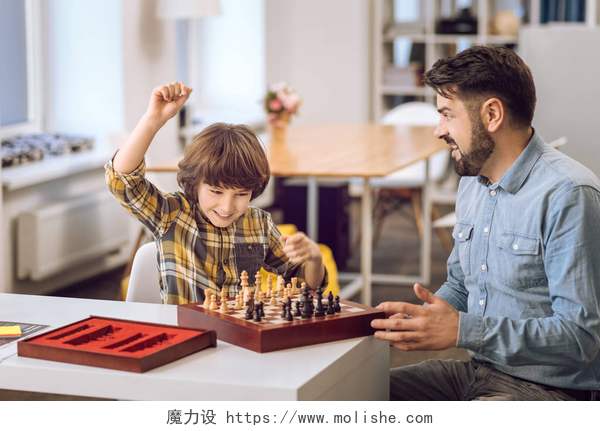 一起玩跳棋的父子两人抱着他的胳膊向上的快乐男孩